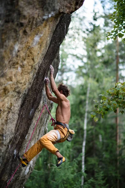 Rock climber falling down while ascending an overhanging. Extreme sport climbing.