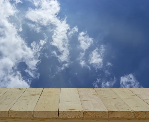 Wood table top on blur background of blue sky and clouds