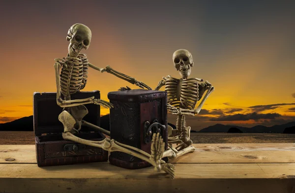 Skeleton pirate sitting on a treasure chest and old wood floor,
