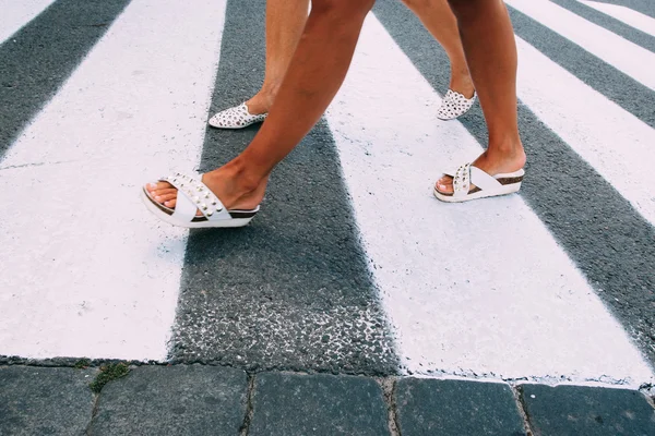 Female legs in white shoes going on zebra