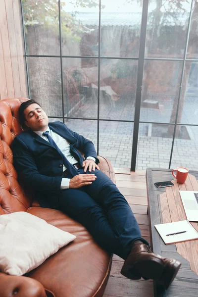 Lazy worker lying on sofa in office