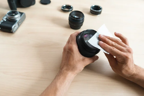 Camera lens cleaning with wet wipe, close-up