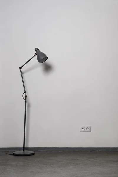 Metal gray floor-lamp near white wall with power socket