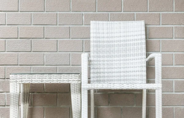 Closeup wood weave table and wood weave chair on blurred brown brick wall texture background , beautiful interior in relaxation of house concept