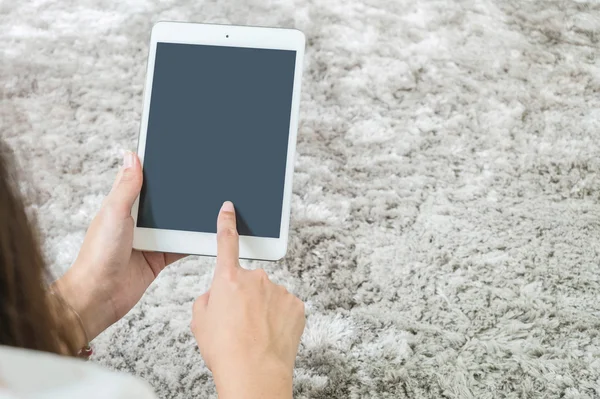 Closeup tablet computer on woman hand on blurred gray carpet floor textured background with copy space
