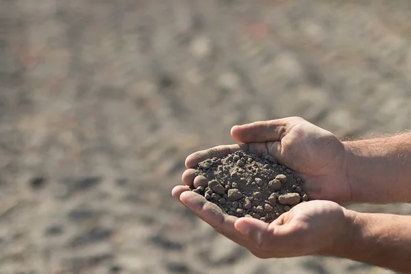Hands holding a pile of soil above the ground. Hands with soil