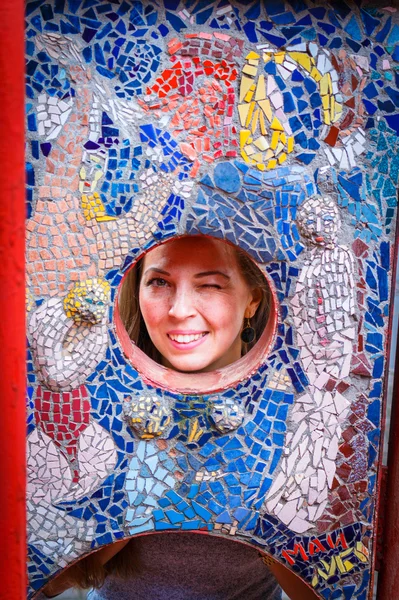 Womans face in a round hole in the mosaic wall.