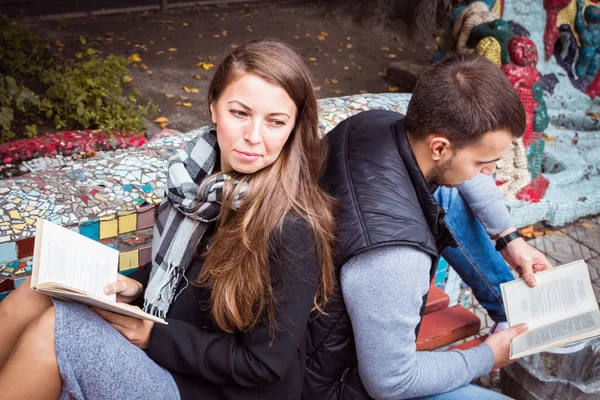 Fashion of nice pretty young hipster woman is sitting back to with a handsome man and reading book