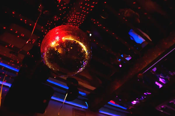 Shining bright red mirror disco ball. Interesting device for discotheque, dancing party with music in night club.
