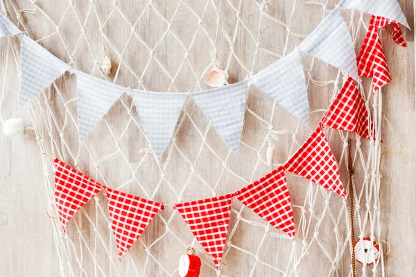 Colorful background with textile flags and fishing net. Sea style decoration with shells and ball floats.