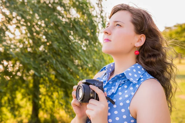Side profile view of young woman holding camera