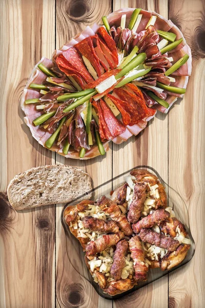 다진된 불고기와 전채 요리 Meze Loafs Cevapcici와 매듭이 소나무 나무 정원 테이블에 닭 허벅지  