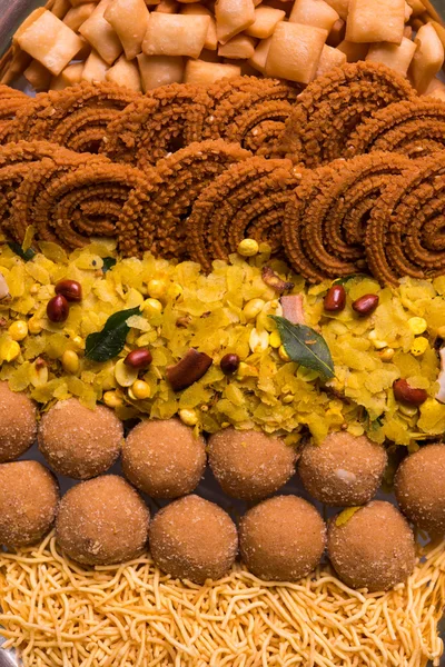 Plate full of indian festival food or diwali food or snacks like laddu, chivda, chakali or murukku, sev and shankar pale, sweet and salty snack food