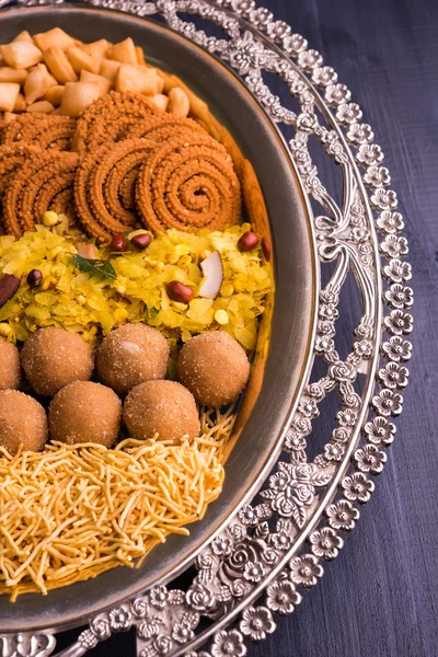 Plate full of indian festival food or diwali food or snacks like laddu, chivda, chakali or murukku, sev and shankar pale, sweet and salty snack food