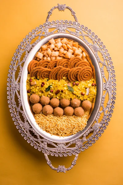 Plate full of indian festival food or diwali food or snacks like laddu, chivda, chakali or murukku, sev and shankar pale, sweet and salty snack food