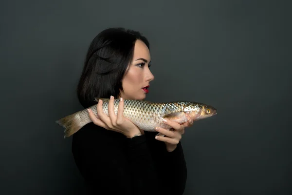 The woman holds live fish in hand