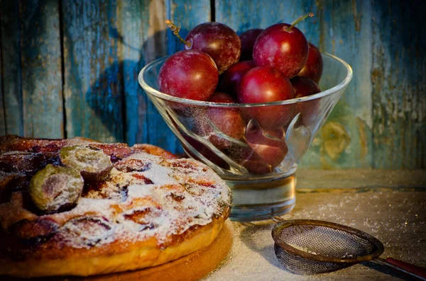 Pialat with plums, plum cake with powdered sugar, a metal strainer