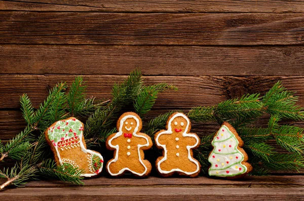 Gingerbread: sock, Christmas tree, gingerbread men. Fur-tree branch against the background of a wooden wall with space for text