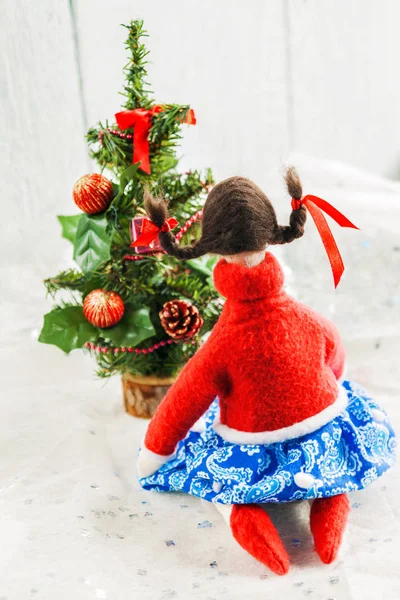 Soft textile doll near a Christmas tree with gifts