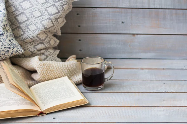 Cushions, plaid, black coffee and old book on the white wooden b