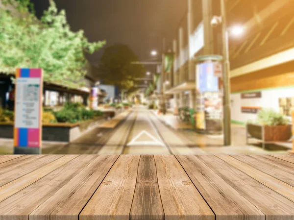Wooden board empty table top on of blurred background. Perspective brown wood table over blur in street city night background - can be used mock up for montage products display or design visual layout