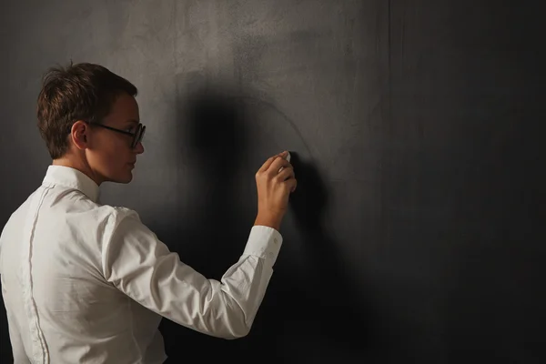 Teacher writing on an empty blackboard