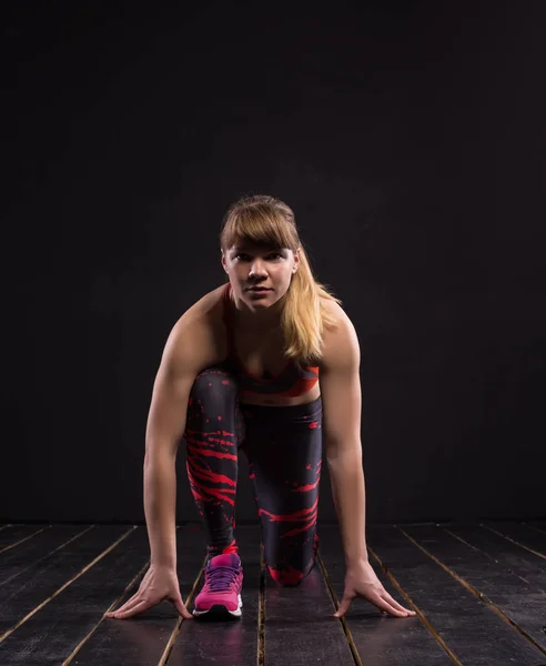 Sport woman posing in photostudio. Fitness motivation picture on dark background