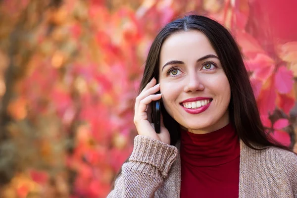 Woman talking on phone in autumn park