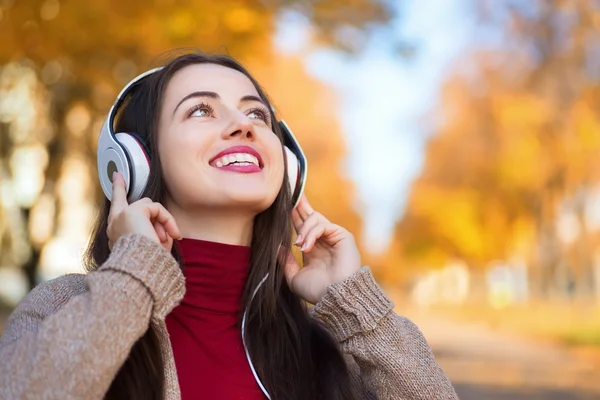 Autumn portrait of happy woman with headphones in park