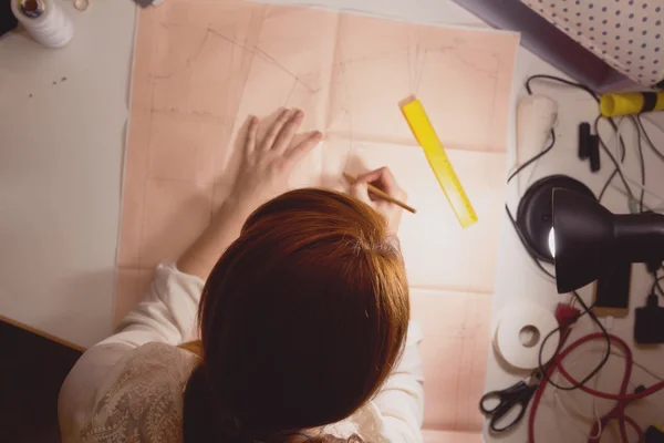 Seamstress draws the pattern on graph paper in the studio