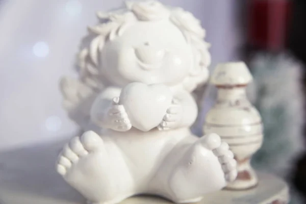 Happy Angel hugging  heart. Ceramic toy.