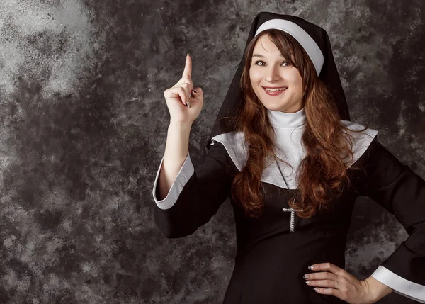 Attractive nun shows the direction of finger up on a dark background
