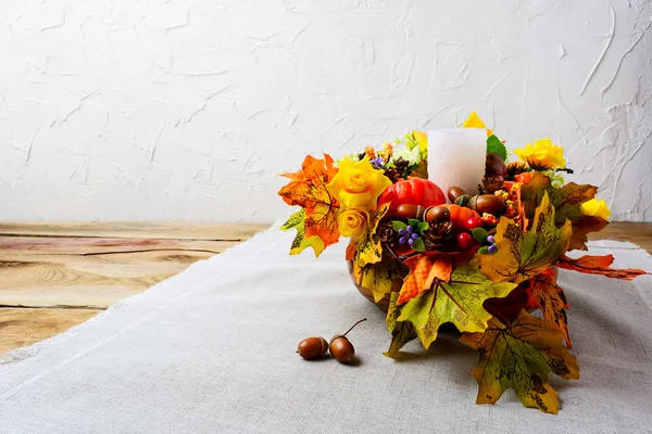 Thanksgiving centerpiece with white candle and silk fall leaves