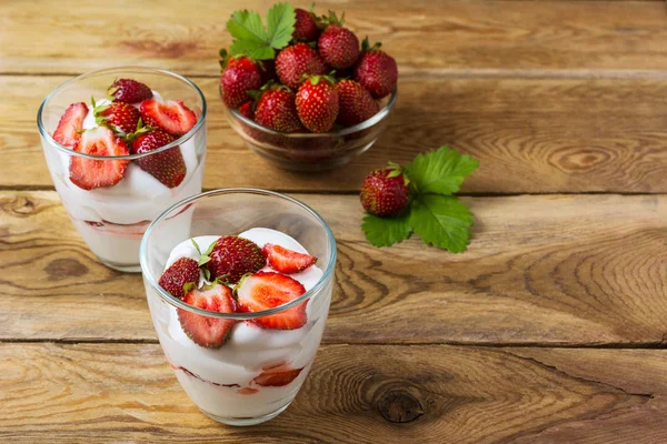 Summer layered cream dessert and ripe strawberry in glass bowl