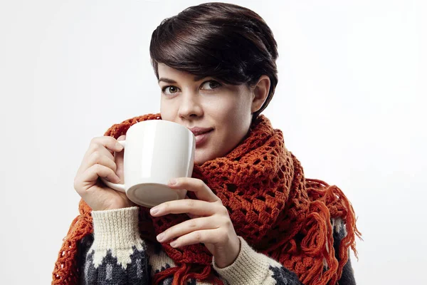 Beautiful young woman with a short brown hair. Hold a white cup of tea or coffee. Look to camera