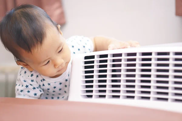 Asian baby curious looking at mobile air conditioner
