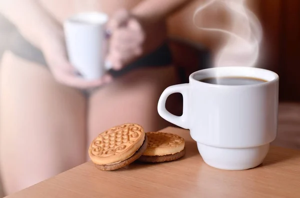 Erotic coffee break. Coffee and biscuits with a blurred silhouette of a sexy girl