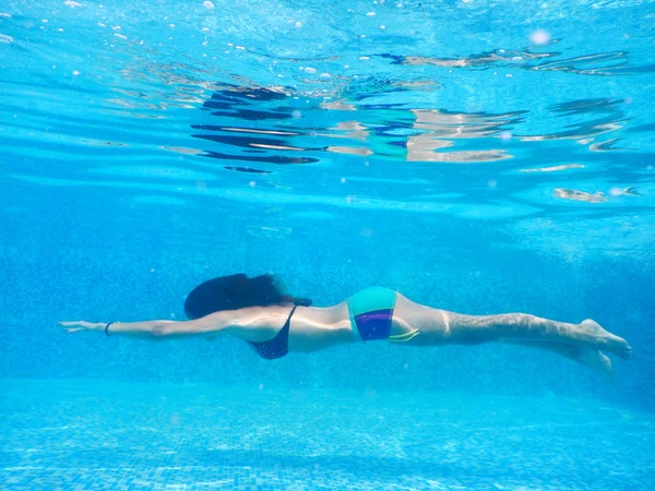 Young woman  swim underwater by the pool