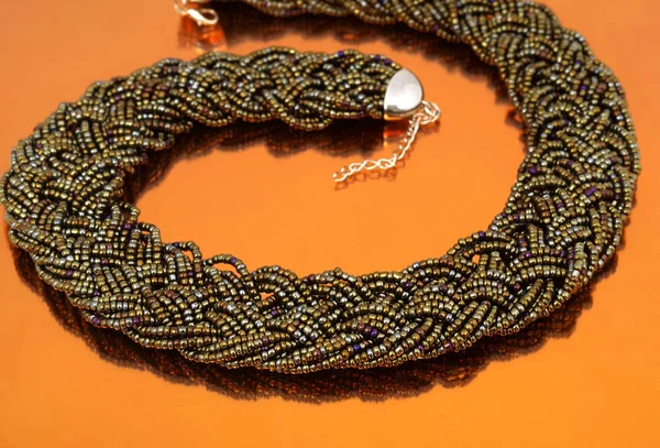 Dark glass bead collar on orange mirror background