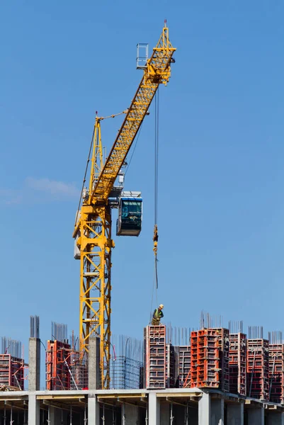 Yellow construction tower crane and house under construction