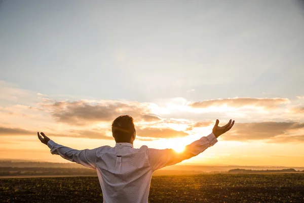 Thankful Businessman with Open Arms at the Field on sunset.