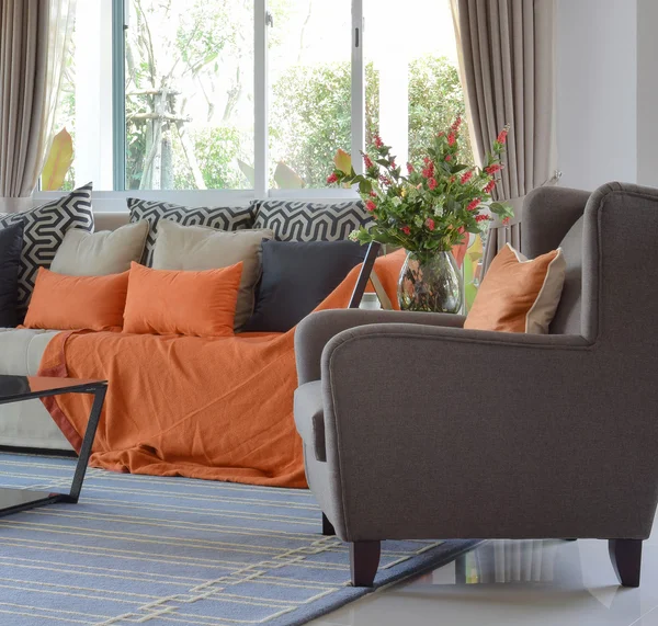 Modern living room design with brown and orange tweed sofa and black pillows