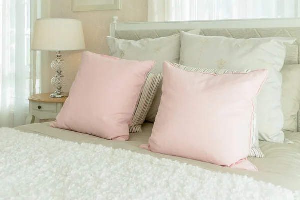 Luxury bedroom interior with pink pillows and reading lamp on bedside table