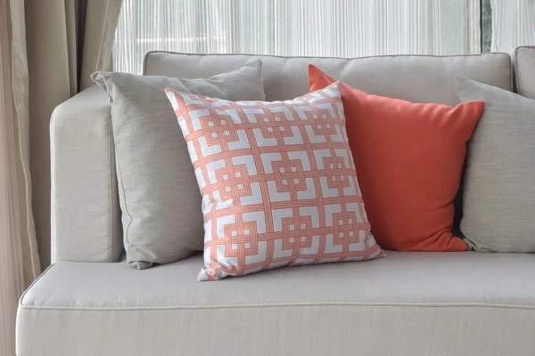Chinese pattern in orange with deep orange and gray pillows on light gray sofa set