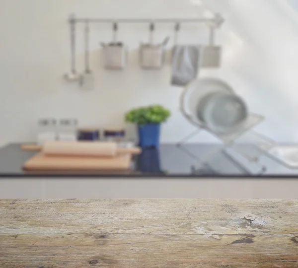 Wooden table top with blur of modern ceramic kitchenware and utensils on the counter top