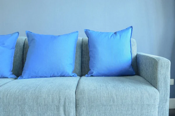Blue color pillows setting on light blue sofa with blue wall