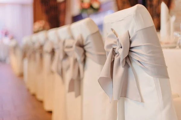 Silk gray bows decorate white chairs