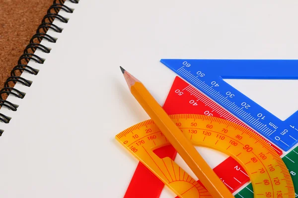 Drawing angles with set squares, pen, notebook and paper on plywood drawing board.