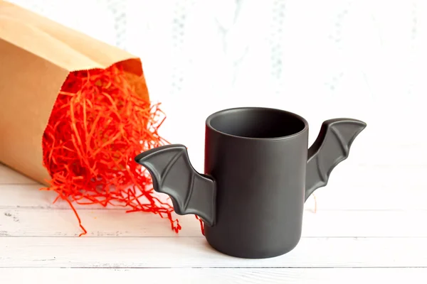 Cup of coffee like a bat in  red paper packaging for Halloween. White background. Toy .  concept.