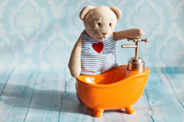 Childrens soft toy teddy bear is bathed in orange bath doll house. Blue bathroom to . Playing with dolls in the family.  bathe in the .